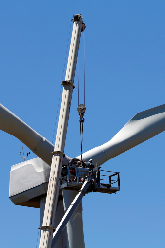 Two operators do maintenance work on a wind turbine