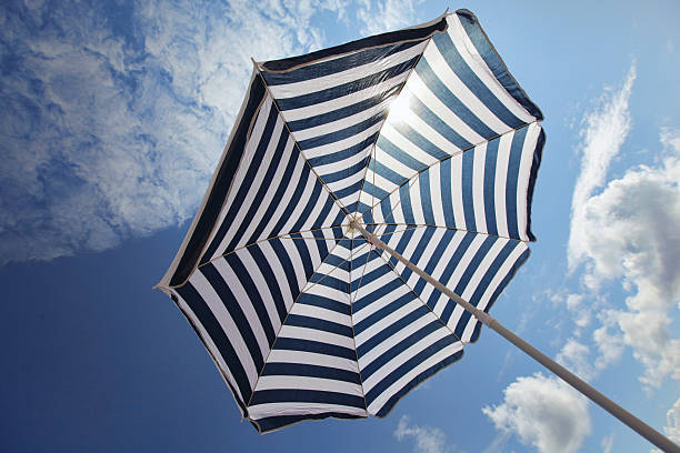 istock Blue and white beach umbrella  on cloudy sky background 186028096