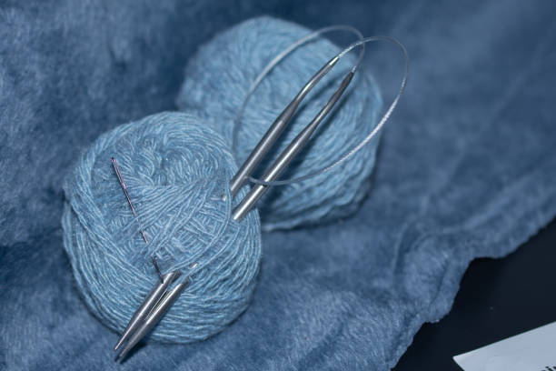 yarn and knitting needle on blue fabric.