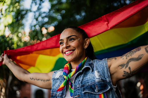 Mid adult woman holding a rainbow flag outdoors