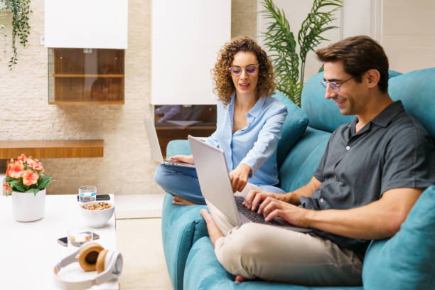 istock Cheerful couple working on laptop while looking at screen in living room 1860384547