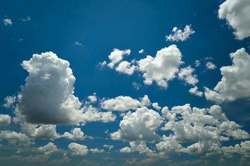 White puffy cumulus clouds on summer blue sky.