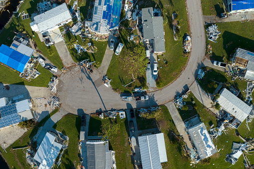 Property damage from strong hurricane winds. Mobile homes in Florida residential area with destroyed rooftops. Consequences of natural disaster.