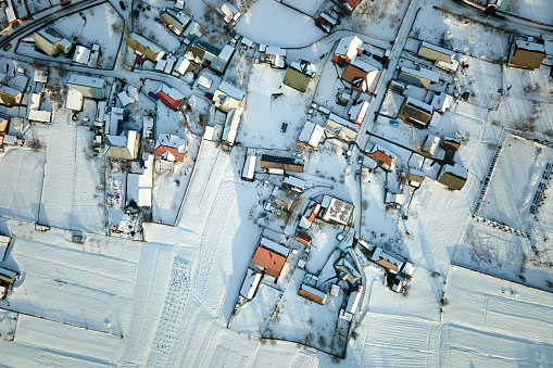 Aerial view of residential houses with snow covered roofops in suburban rural town area in winter.