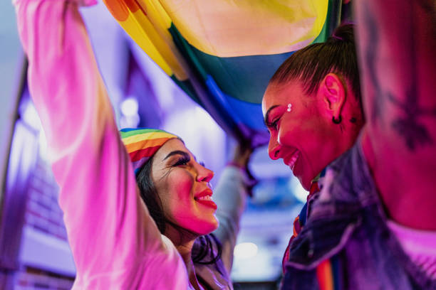 istock Lesbian couple holding a rainbow flag while looking each other 1860398736