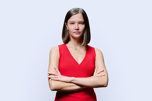 Portrait of young confident woman in red on white studio background. Successful fashionable female with crossed arms looking at camera. Business, work, services, education, fashion beauty professions