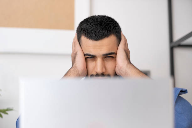 istock Close-up of young man feeling terrible toothache. Handsome young man touching his cheek while working on computer in home office, hurt and suffering from sensitive toothache. 1860507468