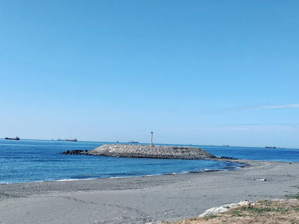istock A small breakwater on the beach with a lighthouse in the background 1860556354
