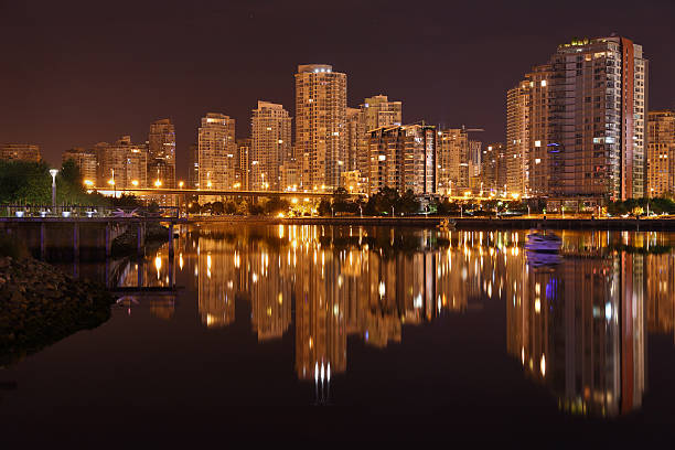 Condominiums reflect in the calm waters of False Creek at night. Vancouver, British Columbia, Canada.