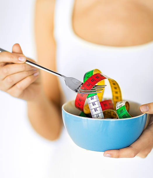 istock woman hands holding bowl with measuring tape 186060621