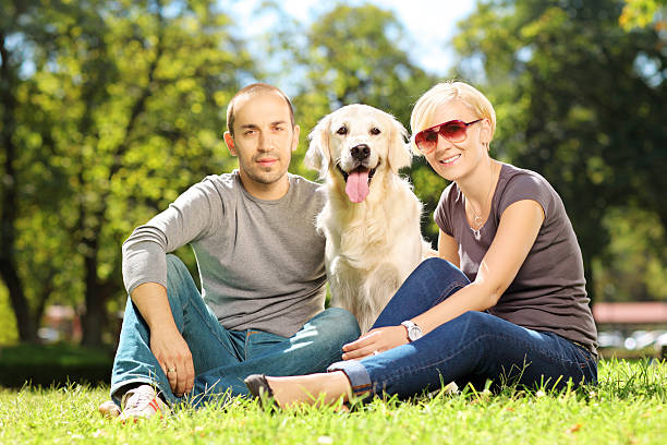 istock Smiling young couple hugging dog in a park 186060782