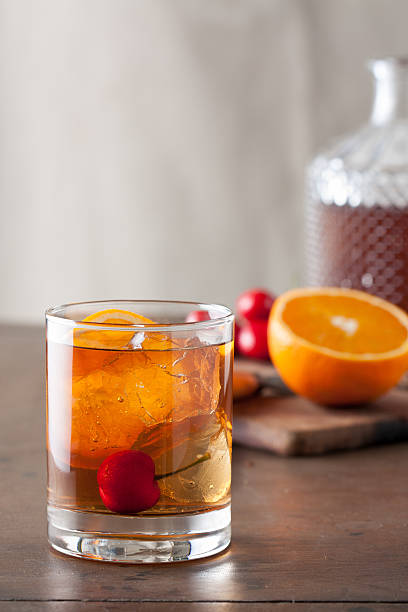 Classic old-fashioned cocktail with a cherry on a wooden table