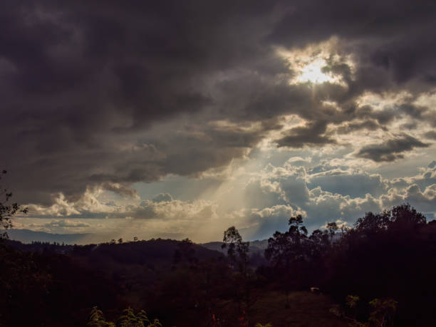A beam of sun light emerges from dense clouds in the sky over the eastern mountains of central Colombian, at the beginning of the sunset.