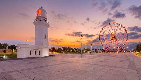 View of the city embankment lighthouse and Ferris wheel in the blue hour during dawn.