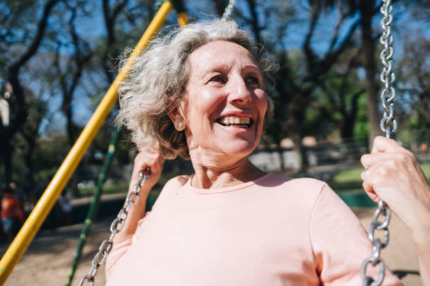 istock Senior woman having fun on swing at public park 1860682759