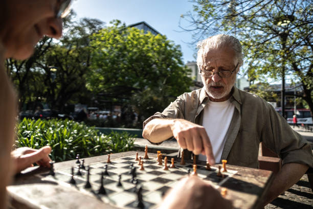 istock Senior man playing chess with his friend in a city square 1860701863