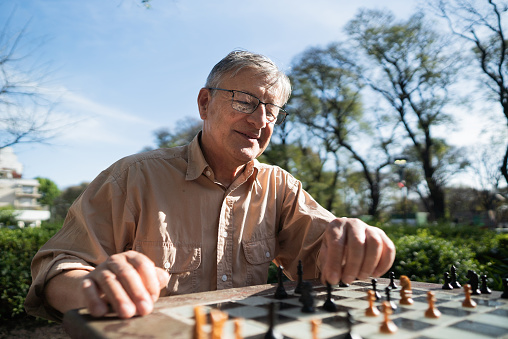 Senior man playing chess in a city square