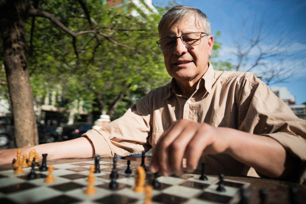 istock Senior man playing chess in a city square 1860702912
