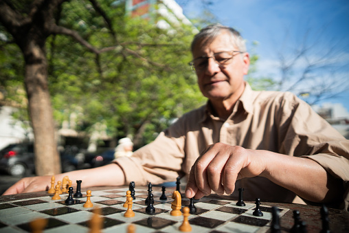 Close-up of a senior man playing chess in a city square