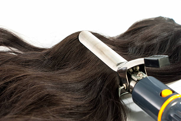 istock Electric curling iron and hair on white background 186072919