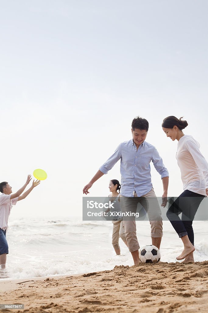 Vier jungen Menschen spielen Fußball und Frisbee am Strand - Lizenzfrei Aktiver Lebensstil Stock-Foto