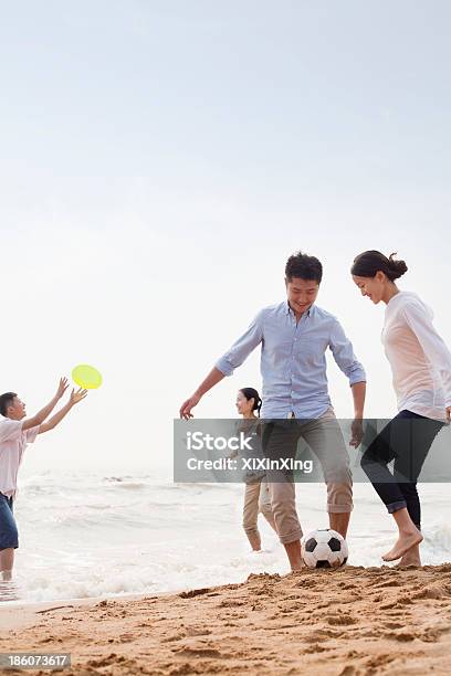 Vier Jungen Menschen Spielen Fußball Und Frisbee Am Strand Stockfoto und mehr Bilder von Aktiver Lebensstil