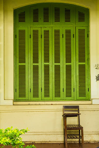 Green vintage wooden windows with student chair, colonial style stock photo