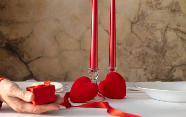 istock Romance in Light, White Table with Candles, Hearts and a Tender Gift Holding. 1860764507