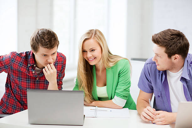 istock smiling students looking to laptop at school 186076902