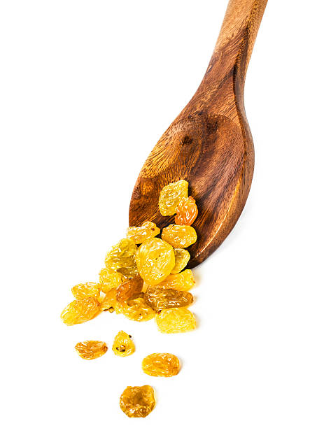 Yellow  Shiny Raisins isolated on white background in a  wooden