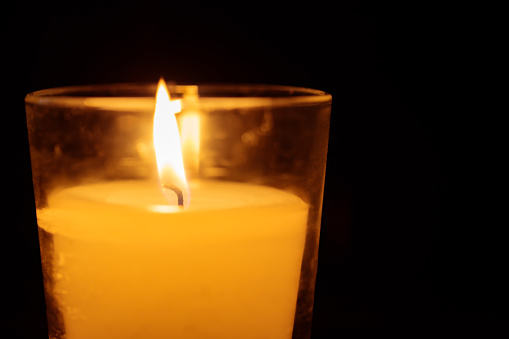 Yellow Candle Burning on Dark Background, Copy Space