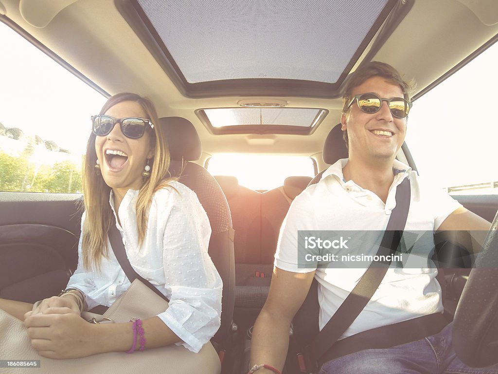 Sonriente joven pareja en un coche con mucha luz - Foto de stock de Coche libre de derechos