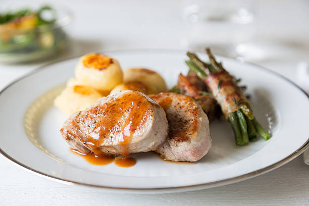 Pork medallions with potatoes and beans on white plate stock photo