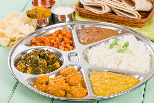South Asian selection of vegetarian curries served in a traditional dish with rice, chapatis, poppadoms, yoghurt and chili sauce.