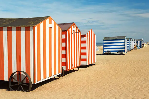 Red and blue stripped huts at a sunny beach.