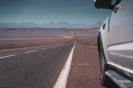 Car on asphalt road on The road going to Valle del Arcoiris in San Pedro de Atacama, Chile