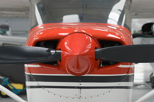 Front part of a red light aircraft with a propeller. Screws, texture, surface, close-up