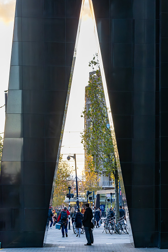 Rotterdam, Netherlands, Nov 11, 2023 A man stands under a large triangle under a skyscraper downtown.