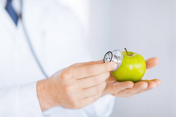 istock male doctor with green apple and stethoscope 186098157