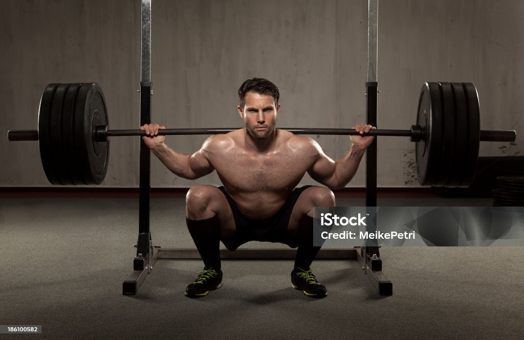 Atleta realiza squat con barra para pesas - Foto de stock de Agacharse libre de derechos