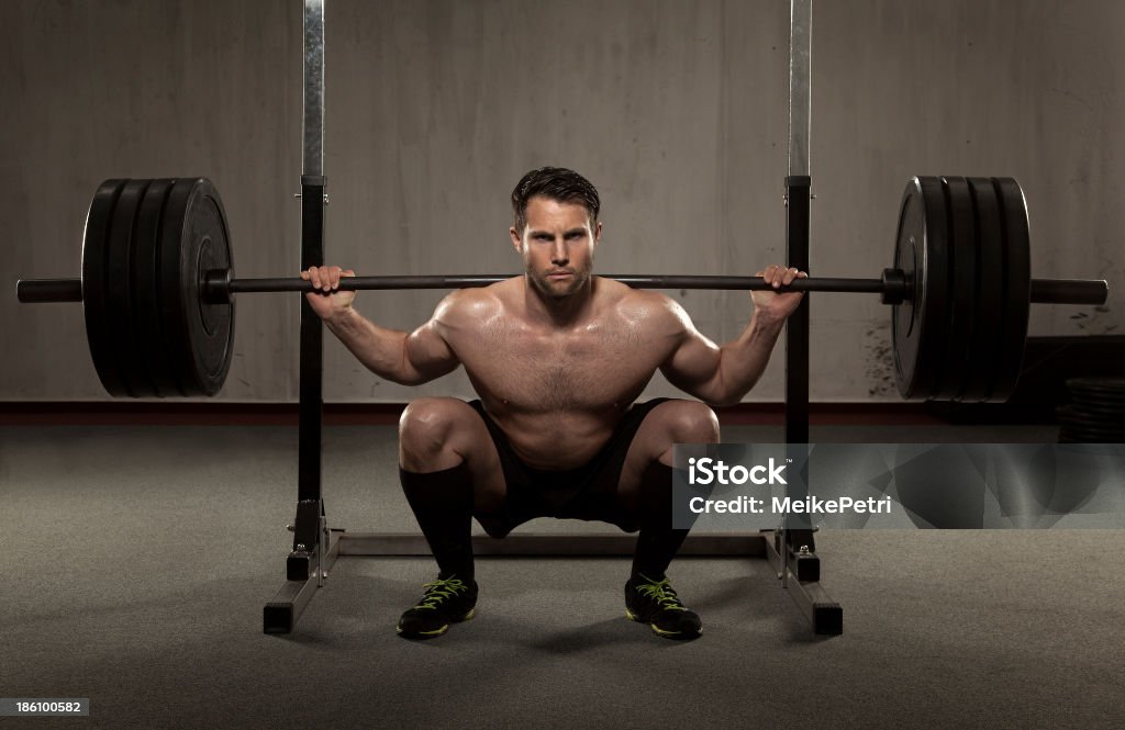 Athlete performing squat with barbell Fit and attractive athlete is performing a squat with a heavy barbell. Active Lifestyle Stock Photo