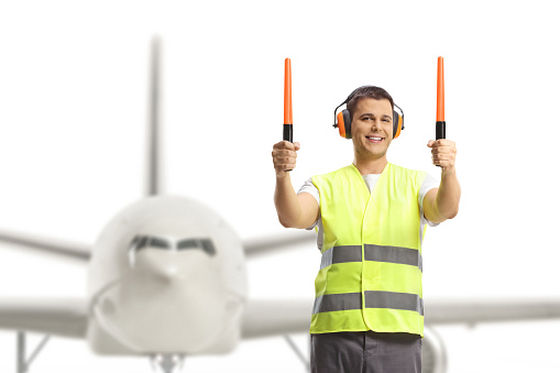 Aircraft marshaller signaling with wands in front of an aircraft