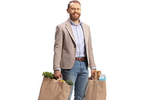 Smiling young man carrying grocery bags isolated on white background