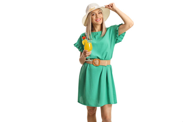 Donna in un vestito verde che tiene un bicchiere di cocktail - foto stock