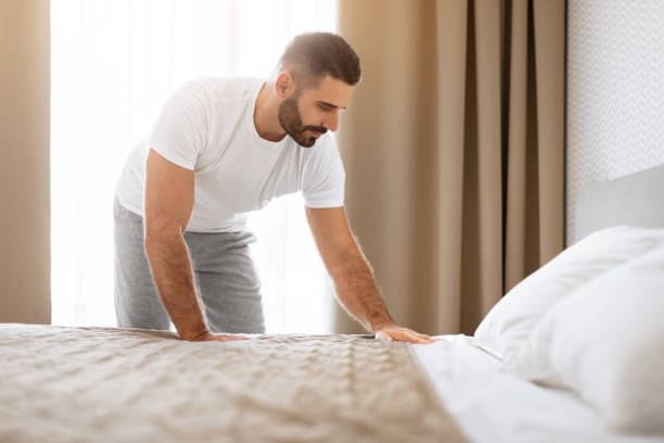 istock Rested Man Making His Bed After Sleep Tidying Modern Bedroom 1861017915