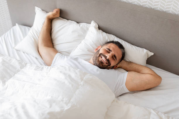 istock man stretching his arms wakes up on cozy bed indoor 1861018411