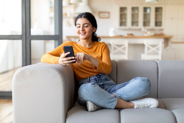 istock Happy Young Indian Female Messaging On Smartphone While Relaxing At Home 1861021215