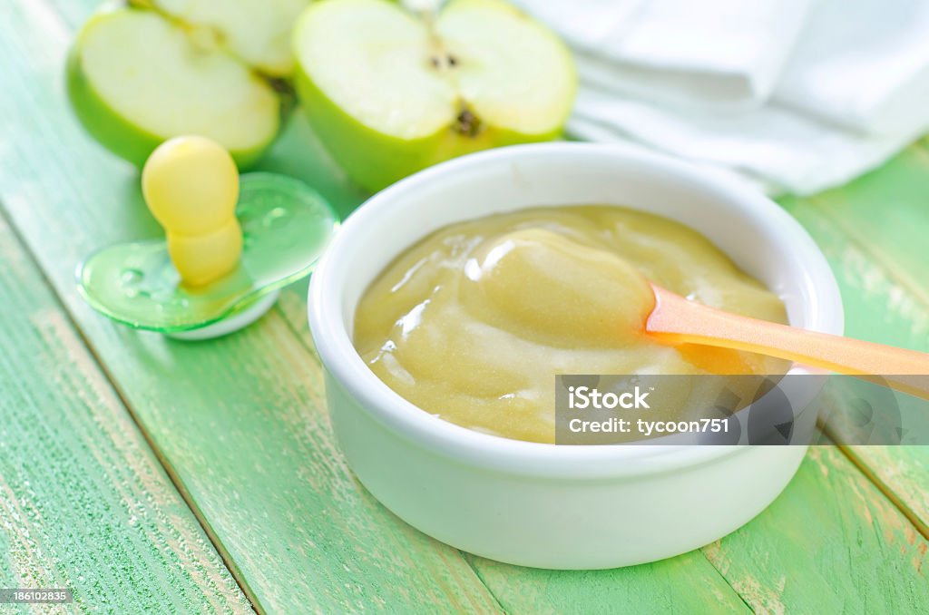 A bowl of baby food with a spoon on a table baby food in bowl Baby - Human Age Stock Photo