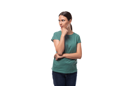 young brunette woman thinking while standing alone.