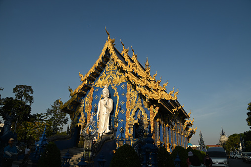 The back of the beauty blue chapel of Wat Rong Suea Ten temple have a large white Buddha image in the forbidding posture. Located Chiang Rai Province in Thailand.